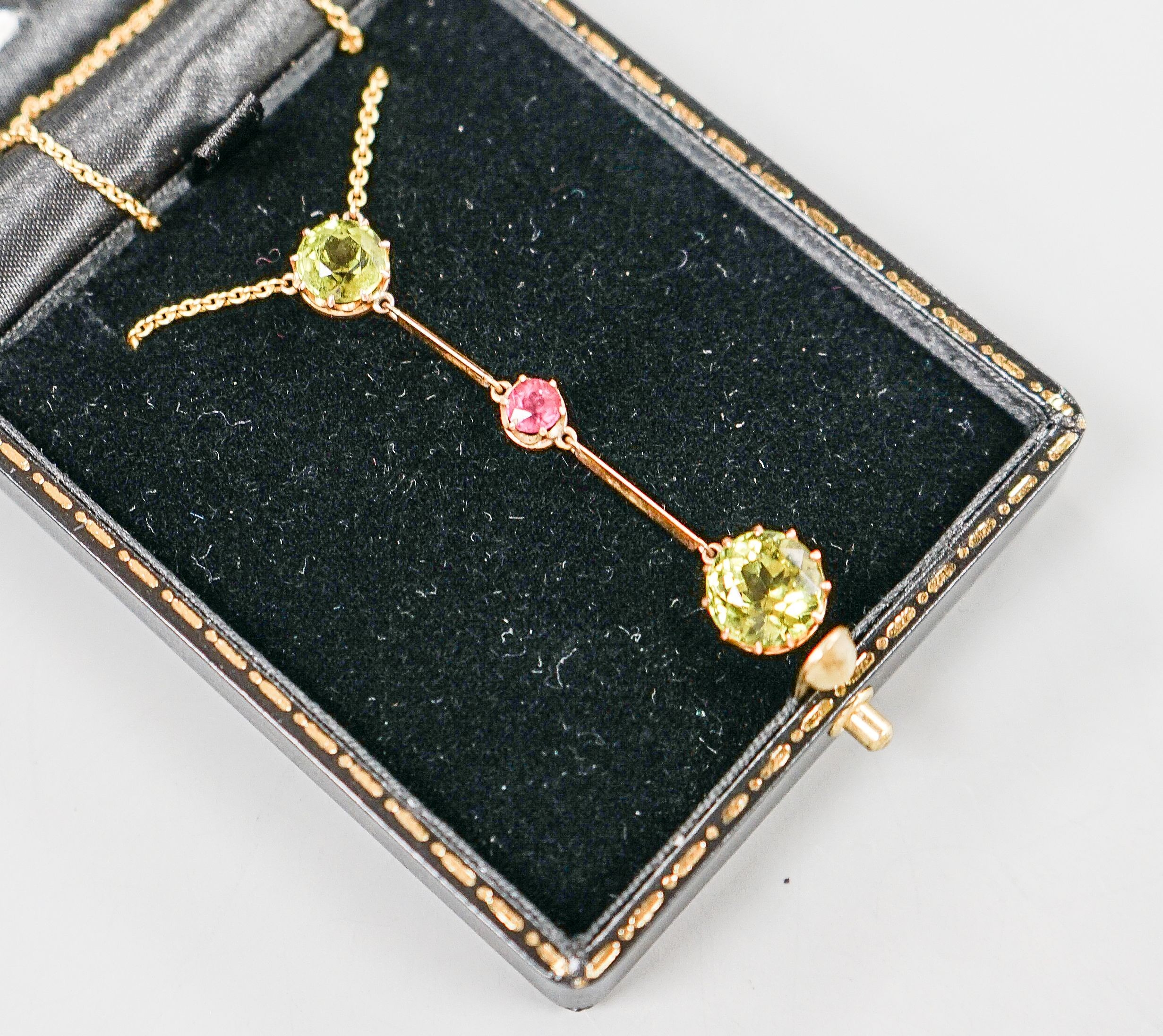 A 20th century yellow metal, two stone peridot and single stone pink tourmaline? set drop line pendant necklace, 51cm, gross 5.5 grams.